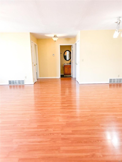 Unfurnished living room featuring light wood-style flooring, visible vents, and baseboards