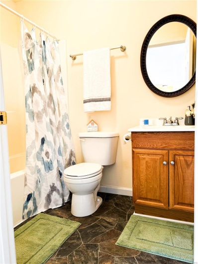 Full bathroom with baseboards, vanity, toilet, and shower / bath combo with shower curtain