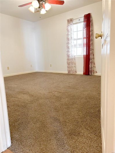 Empty room featuring carpet floors, baseboards, and a ceiling fan