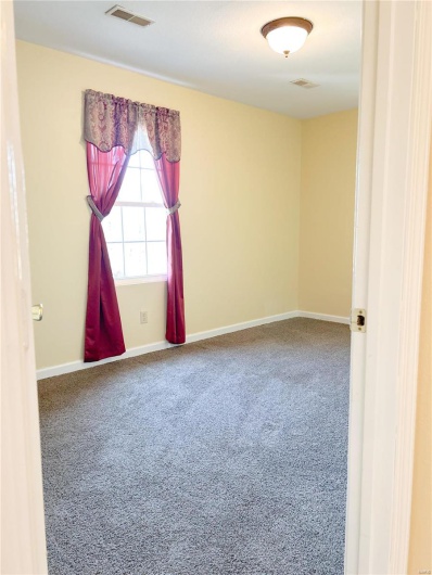 Carpeted spare room featuring visible vents and baseboards