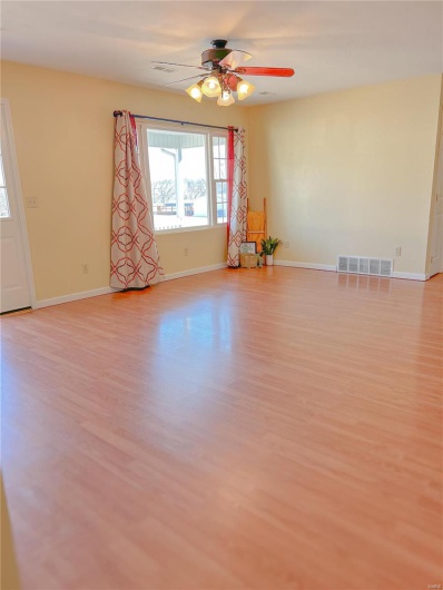 Unfurnished room featuring visible vents, ceiling fan, light wood-style flooring, and baseboards