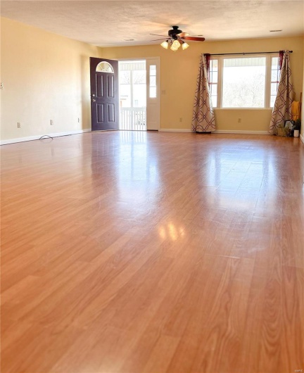 Empty room featuring a ceiling fan, a textured ceiling, baseboards, and wood finished floors