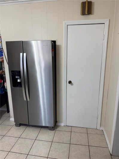 Kitchen featuring light tile patterned floors and stainless steel fridge with ice dispenser
