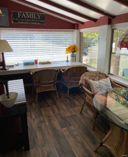Sunroom / solarium featuring built in desk and lofted ceiling with beams