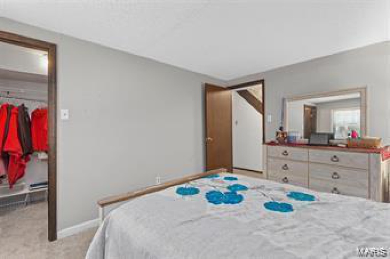 Bedroom featuring light carpet and a walk in closet
