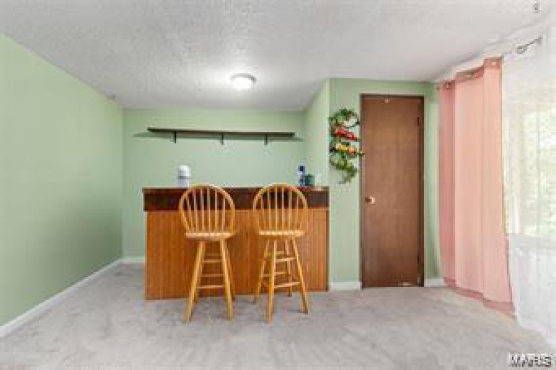 Kitchen featuring light colored carpet, a breakfast bar, and a textured ceiling