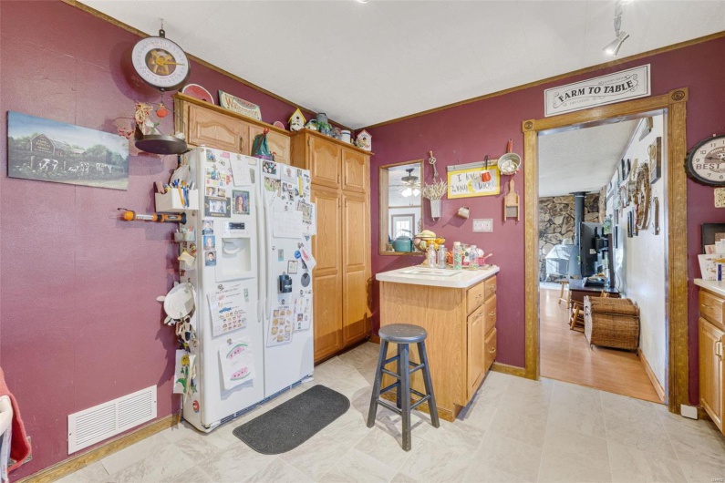 Kitchen featuring a breakfast bar area, track lighting, white fridge with ice dispenser, kitchen peninsula, and a wood stove