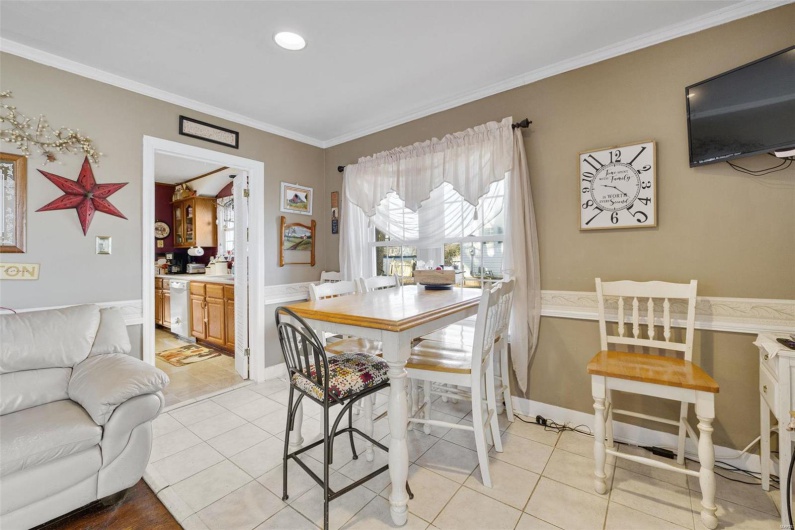 Dining space with crown molding and light tile patterned floors