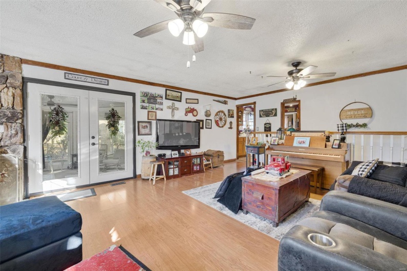 Living room featuring ornamental molding, ceiling fan, light hardwood / wood-style floors, a textured ceiling, and french doors