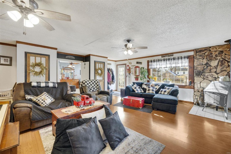 Living room with crown molding, ceiling fan, light hardwood / wood-style flooring, and a textured ceiling