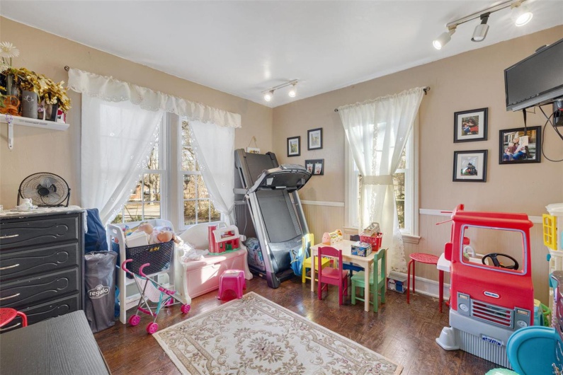 Playroom with dark wood-type flooring and track lighting