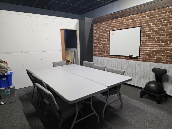 Carpeted office space with wainscoting and brick wall