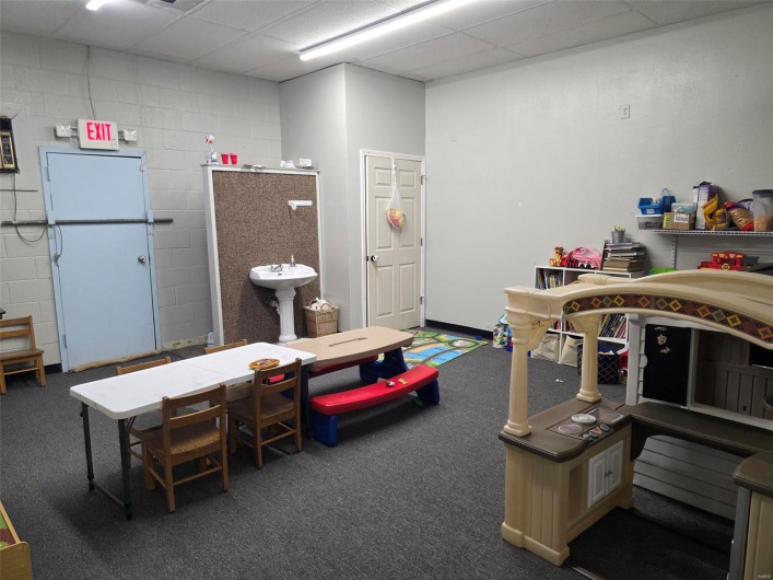 Rec room featuring a paneled ceiling, carpet, and concrete block wall