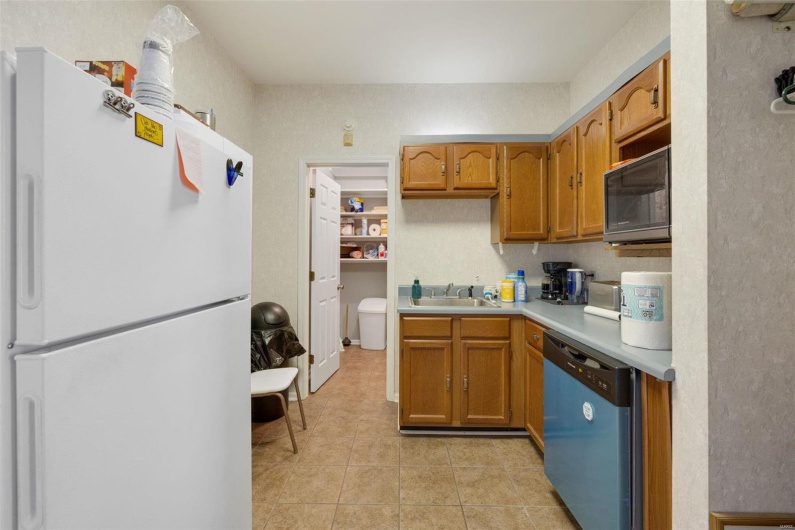 Kitchen with dishwashing machine, sink, white fridge, and light tile patterned floors