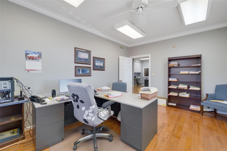 Home office featuring crown molding, ceiling fan, and light wood-type flooring