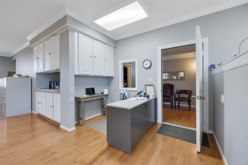 Kitchen featuring white cabinetry, ornamental molding, light hardwood / wood-style floors, and kitchen peninsula