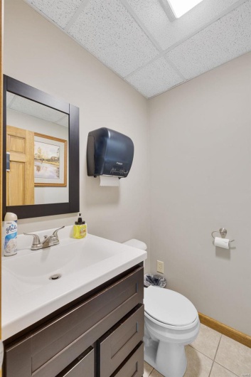 Bathroom featuring vanity, tile patterned flooring, toilet, and a drop ceiling