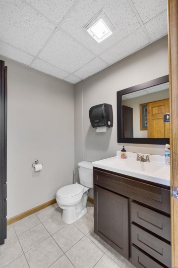 Bathroom with tile patterned flooring, vanity, a paneled ceiling, and toilet