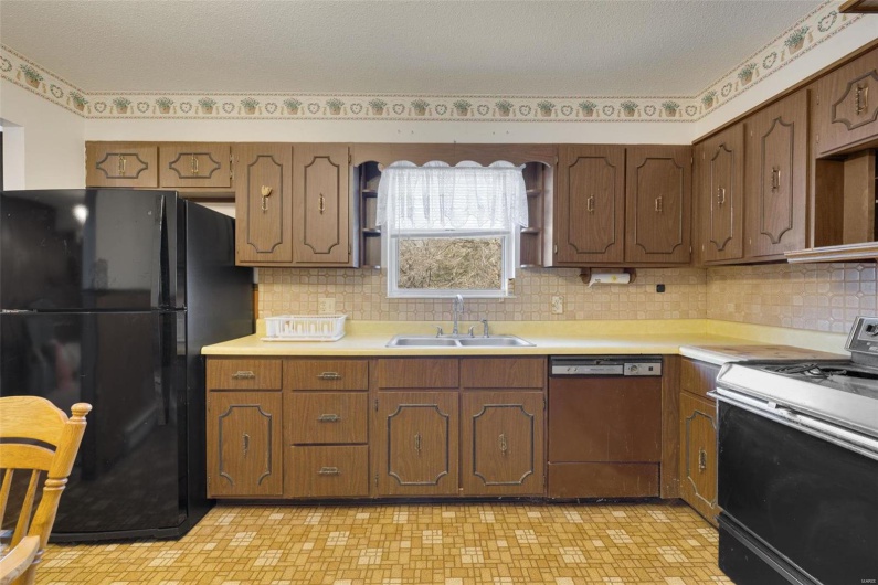 Kitchen with tasteful backsplash, sink, black appliances, and a textured ceiling