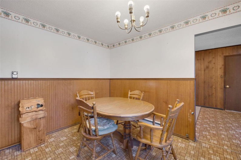 Dining area featuring wooden walls, a textured ceiling, and a chandelier