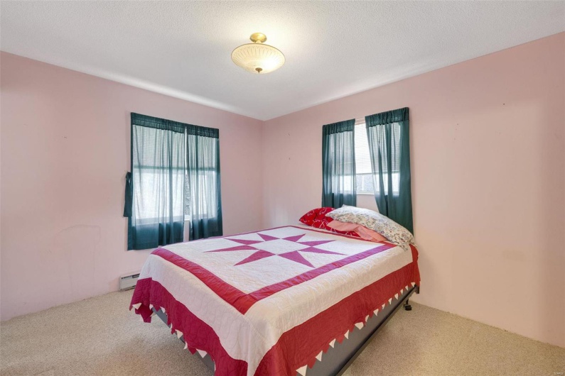 Bedroom with a baseboard heating unit, light colored carpet, and a textured ceiling