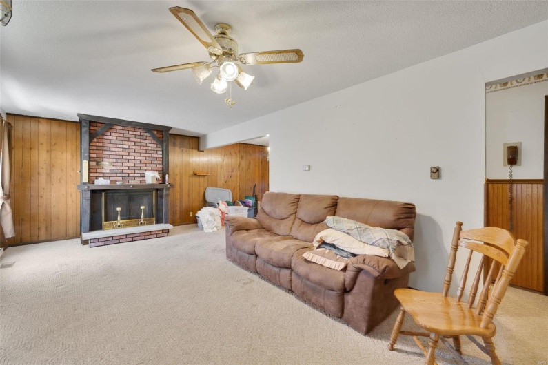 Living room featuring light carpet, ceiling fan, and wood walls