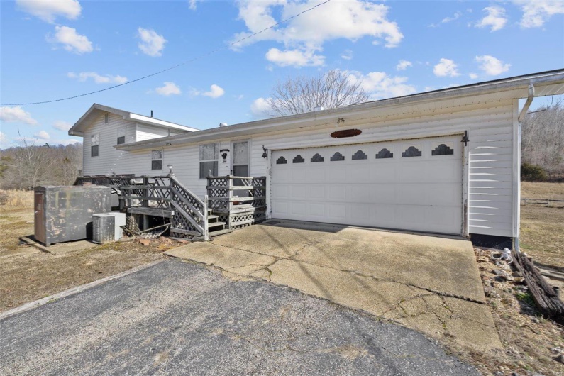 Single story home with a wooden deck, a garage, and cooling unit