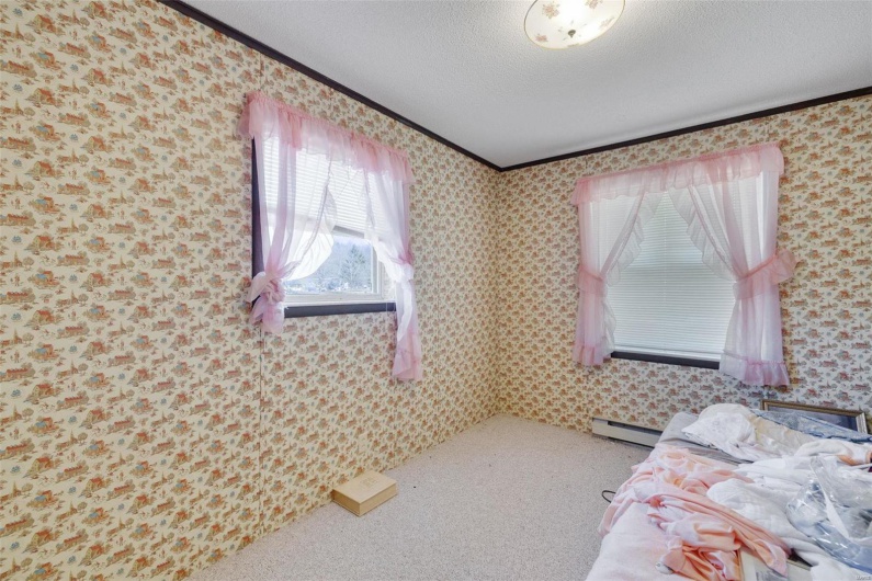 Carpeted bedroom featuring crown molding, a textured ceiling, and a baseboard heating unit