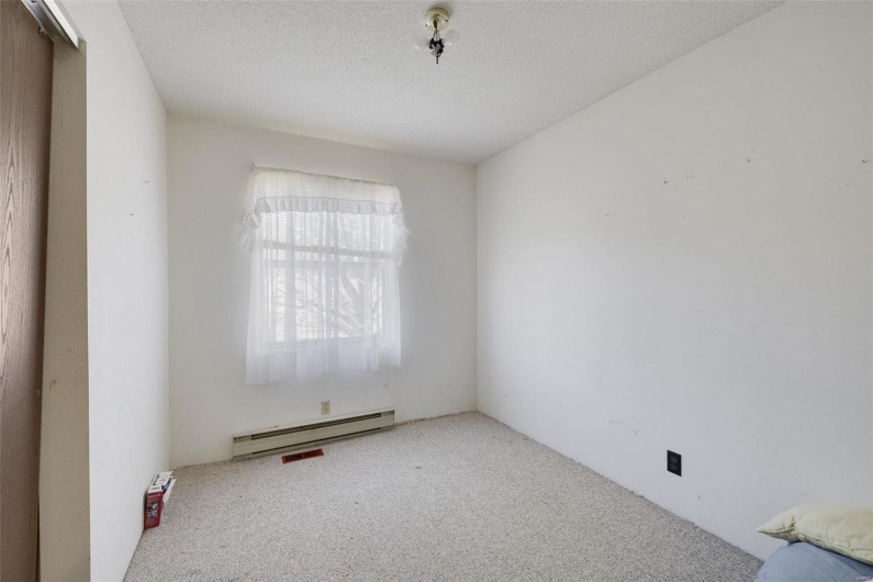 Carpeted empty room featuring a baseboard heating unit and a textured ceiling