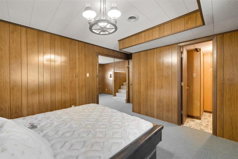 Carpeted bedroom with a chandelier and wood walls