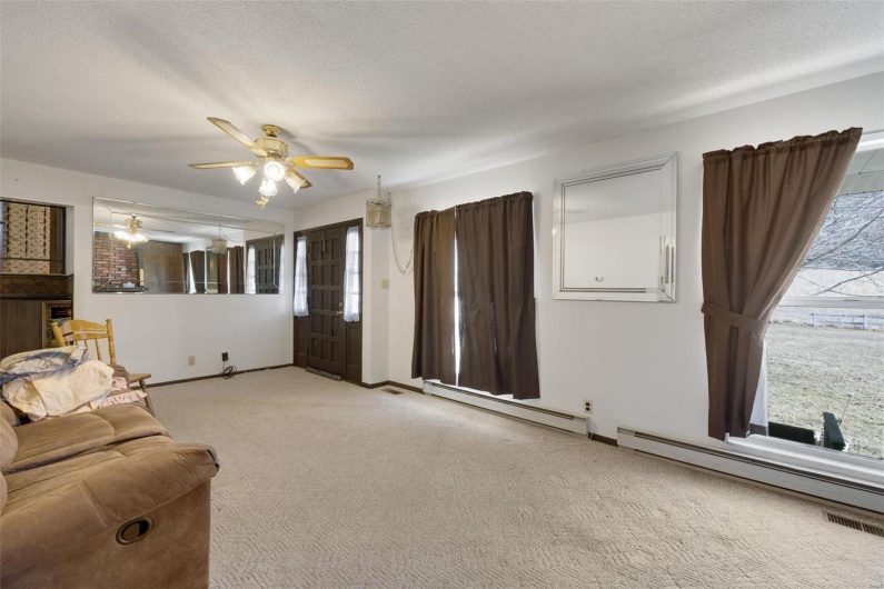 Living room featuring a baseboard radiator, light colored carpet, and a textured ceiling