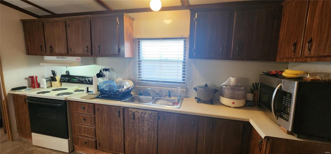 Kitchen with dark brown cabinets, sink, and electric range