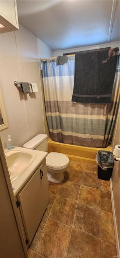 Full bathroom with shower / bath combination with curtain, vanity, and toilet