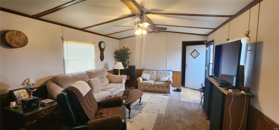 Living room featuring crown molding, ceiling fan, and lofted ceiling with beams