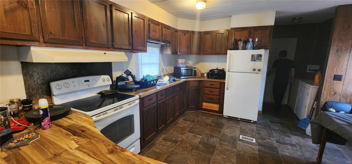 Kitchen featuring dark brown cabinetry, washer / dryer, wooden counters, and white appliances