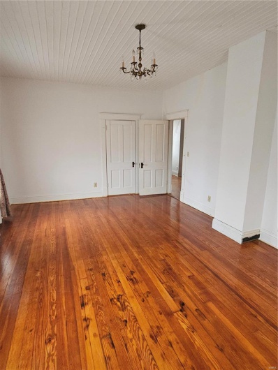 Unfurnished room with hardwood / wood-style floors and a notable chandelier