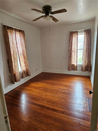 Spare room with dark wood-type flooring and ceiling fan