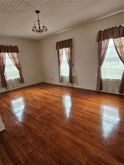 Empty room with a notable chandelier and wood-type flooring