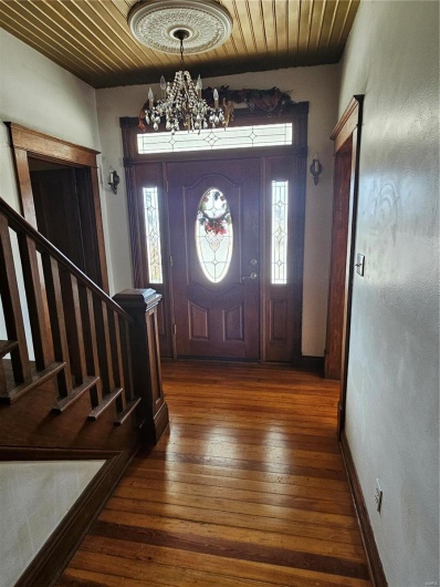 Entrance foyer featuring an inviting chandelier, wood ceiling, plenty of natural light, and dark hardwood / wood-style floors