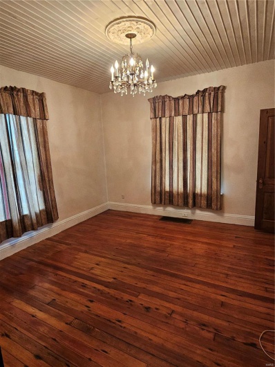 Spare room with dark wood-type flooring, wooden ceiling, and an inviting chandelier