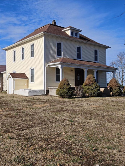 Back of property featuring a porch, a garage, and a yard