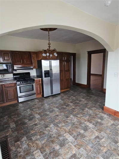 Kitchen with stainless steel refrigerator with ice dispenser, dark brown cabinetry, exhaust hood, and stove