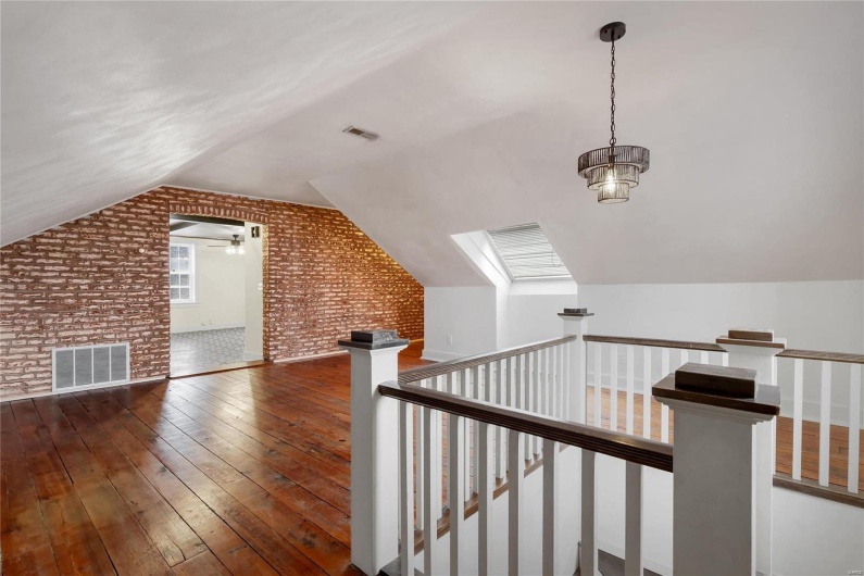 Third floor studio. Dark hardwood / wood-style flooring and vaulted ceiling with skylight