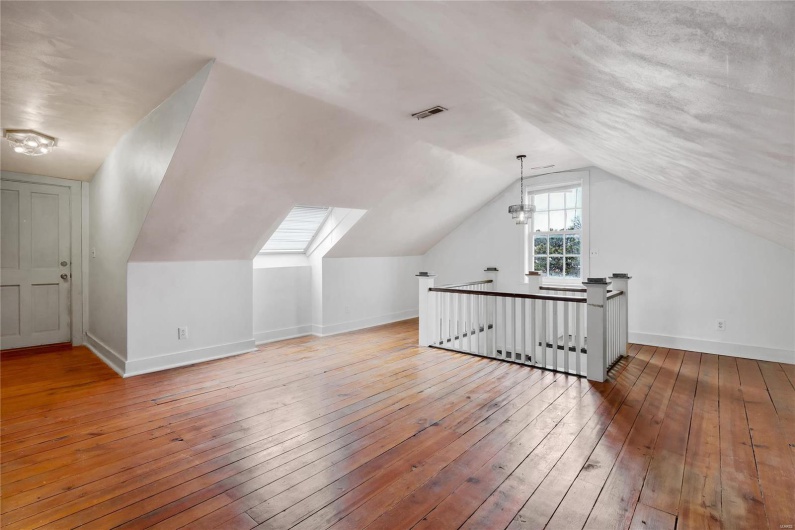 Third floor studio. Additional living space featuring vaulted ceiling and hardwood / wood-style floors