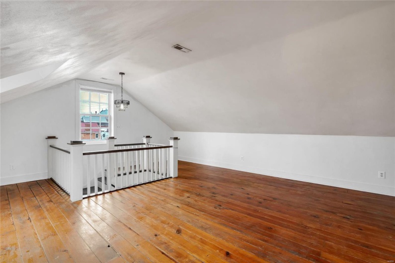 Third floor studio. Additional living space featuring wood-type flooring and vaulted ceiling