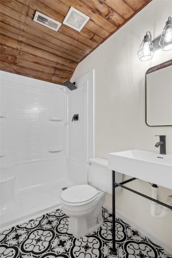 Third floor studio. Bathroom featuring wood ceiling, toilet, tile patterned flooring, and a shower