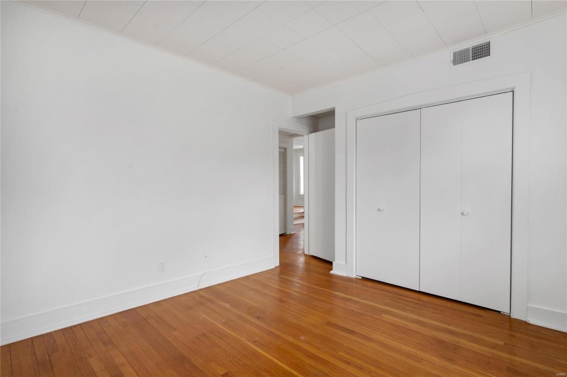 Second floor apartment. Unfurnished bedroom featuring hardwood / wood-style floors, ornamental molding, and a closet