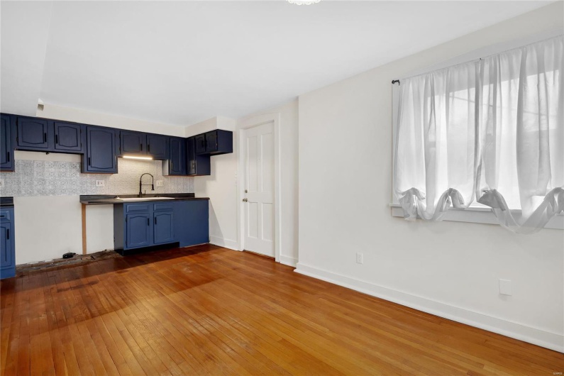 Second floor apartment. Kitchen featuring blue cabinetry, sink, dark hardwood / wood-style floors, and decorative backsplash
