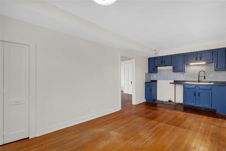 Second floor apartment. Kitchen featuring tasteful backsplash, blue cabinets, dark hardwood / wood-style floors, and sink