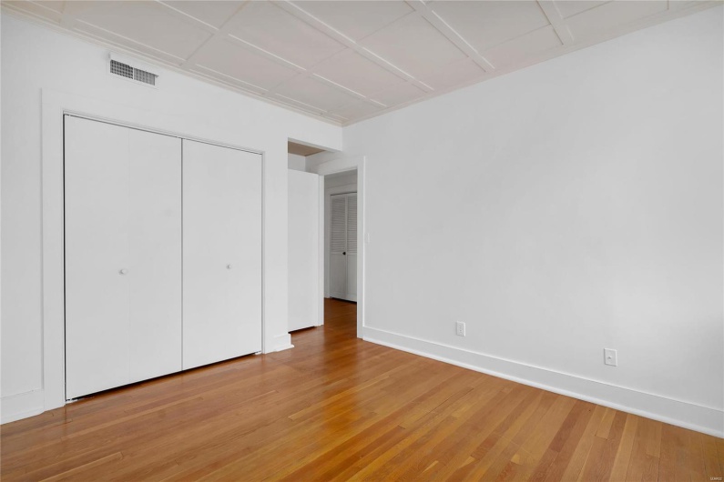 Second floor apartment. Unfurnished bedroom featuring hardwood / wood-style flooring and a closet
